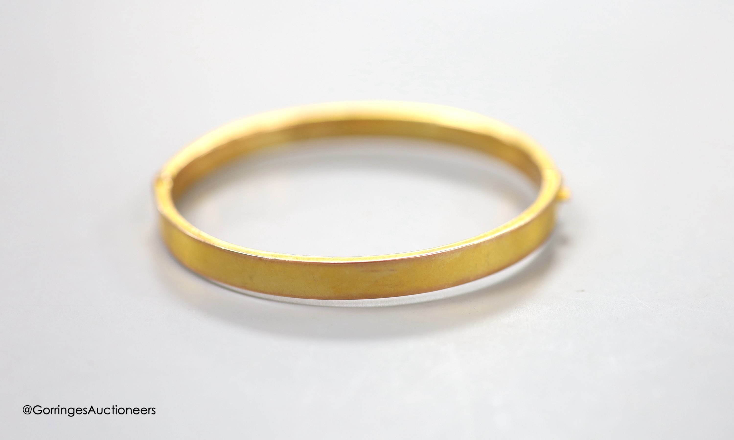 A George V 9ct gold hinged bangle, with engraved initials, 9.1 grams.